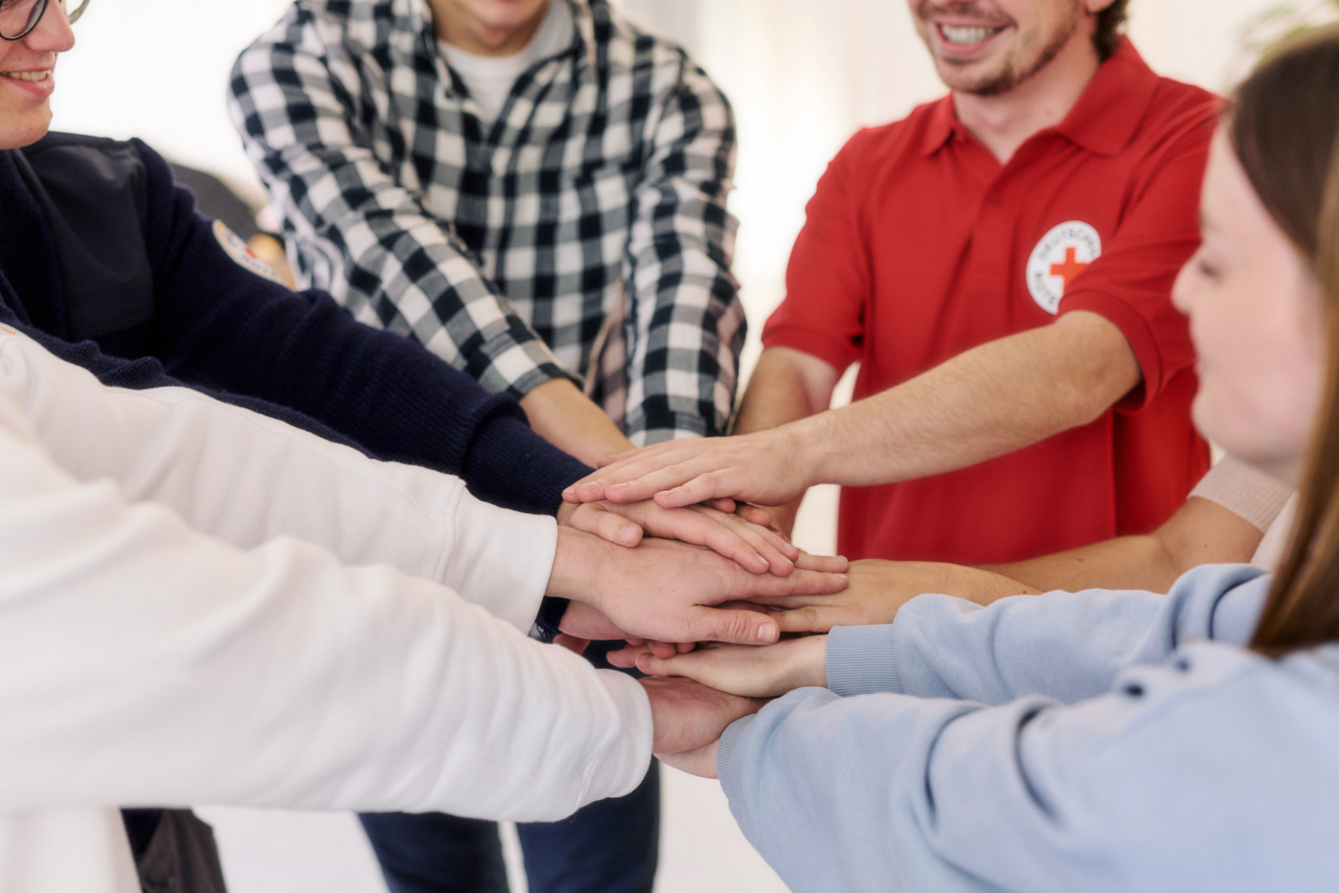 Eine Gruppe Menschen steht im Kreis und legt als Team die Hände übereinande